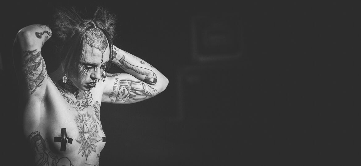 Personne tatouée en noir et blanc, bras levés.