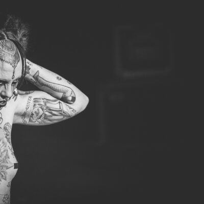 Personne tatouée en noir et blanc, bras levés.