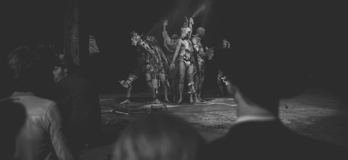 Performance artistique en noir et blanc, public observant.