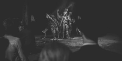 Performance artistique en noir et blanc, public observant.