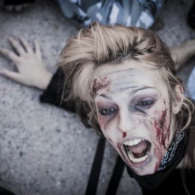 Personne maquillée en zombie effrayée au sol.