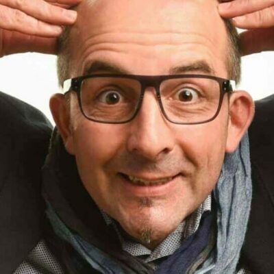 Homme chauve souriant touchant sa tête.