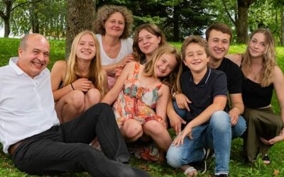 Famille souriante assise sur l'herbe sous les arbres.