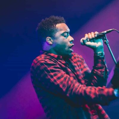 Musicien chante en concert, ambiance lumineuse.