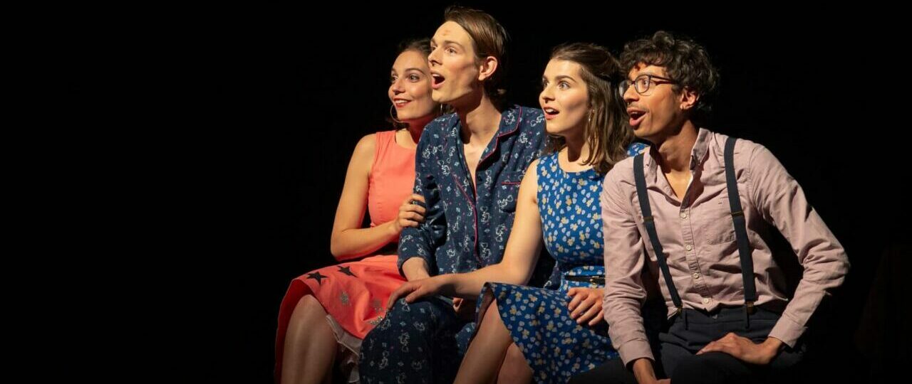 Quatre personnes souriantes sur une scène de théâtre.