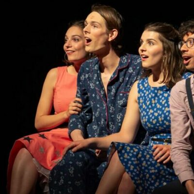 Quatre personnes souriantes sur une scène de théâtre.