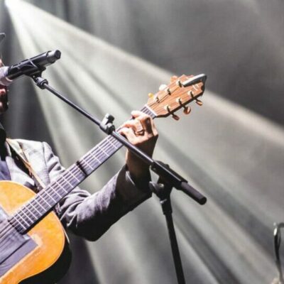 Homme jouant de la guitare sur scène illuminée.