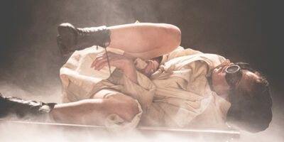 Personne en tenue vintage, lunettes, couche sur scène.