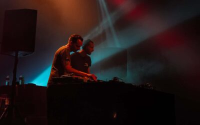 Deux DJ sur scène avec lumières colorées.
