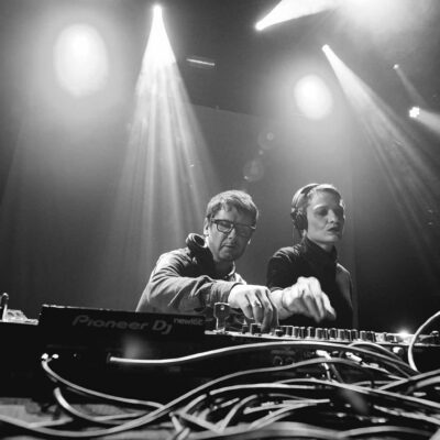 Deux DJ mixant sur scène, éclairage intense.
