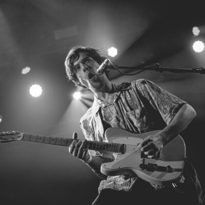 Homme jouant de la guitare sur scène.