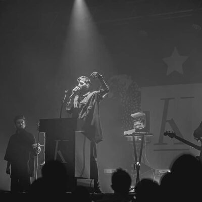 Concert en noir et blanc, chanteur sur scène.