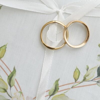 Coussinet blanc avec bagues dorées et décor floral.