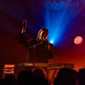 Musicien joue du clavier sur scène illuminée.