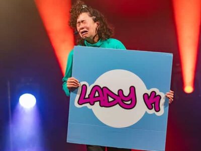 Personne tenant panneau Lady K1 sur scène colorée.