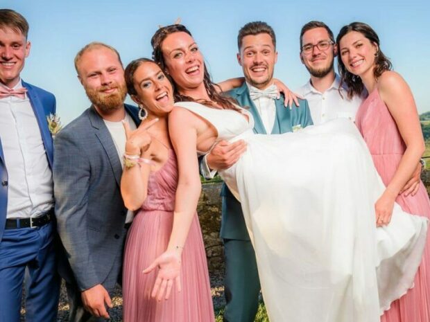 Mariage : amis portant la mariée souriante.