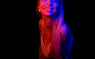 Femme souriante sous lumière colorée.