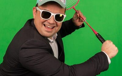 Homme en costume, jouant badminton, fond vert.