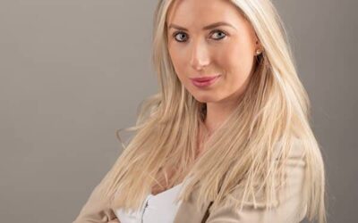 Femme blonde en blazer beige, bras croisés.