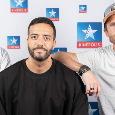 Trois hommes devant un fond Kinepolis.