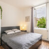 Chambre avec lit double, fenêtre ouverte, armoire miroir.