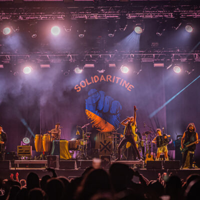 Concert avec éclairage coloré et décor 'Solidaritine'.