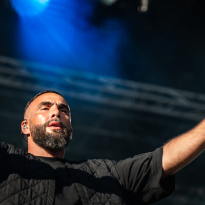 Chanteur en concert, lumières vives sur scène.