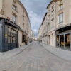Rue avec bâtiments historiques et magasins.