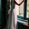 Femme en robe de mariée regardant par la fenêtre.