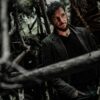 Homme debout dans une forêt sombre.