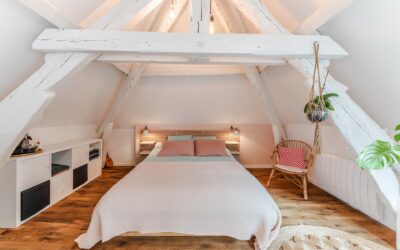 Chambre mansardée avec lit et poutres apparentes.