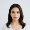 Femme aux cheveux bruns, regard neutre, fond clair.