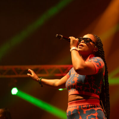 Chanteuse en concert avec micro et lunettes.