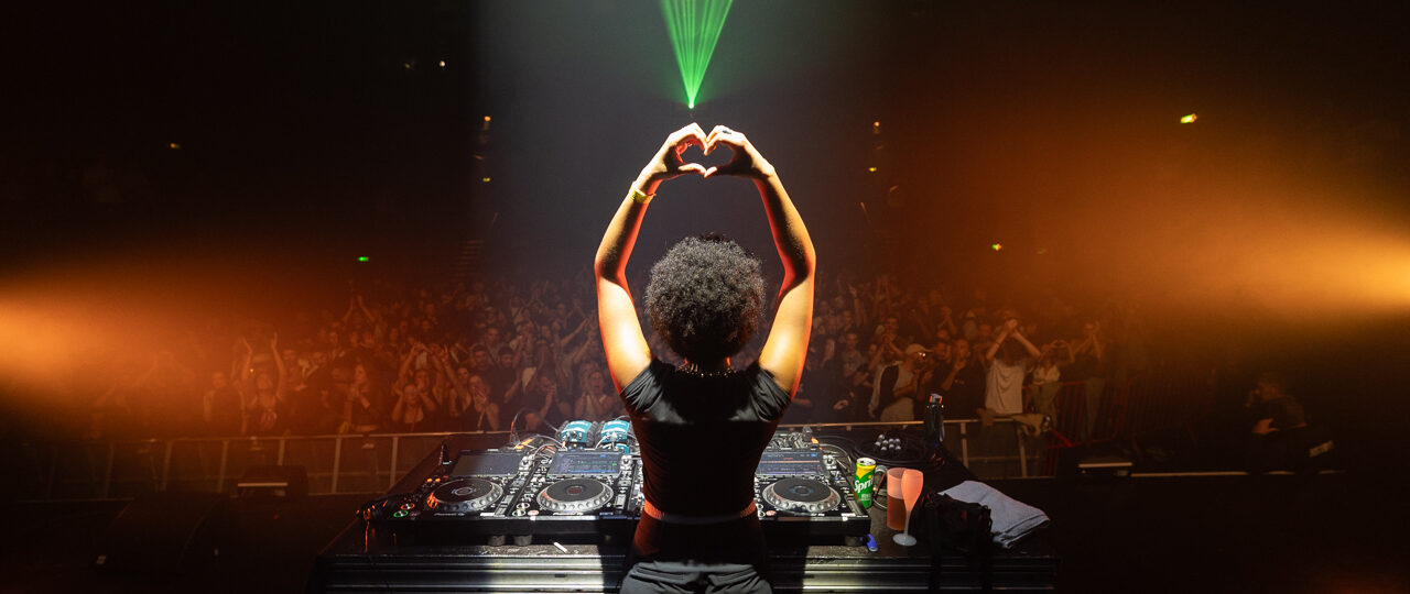 DJ sur scène devant foule enthousiaste.