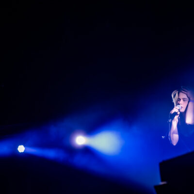 Chanteur sur scène avec lumière bleue intense.