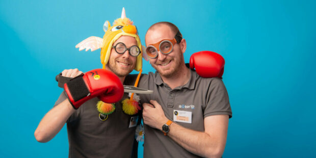 Deux hommes souriant avec déguisements et jouets.
