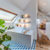 Salle de bain lumineuse avec plantes et baignoire.