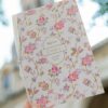 Faire-part de baptême fleuri tenu en main.