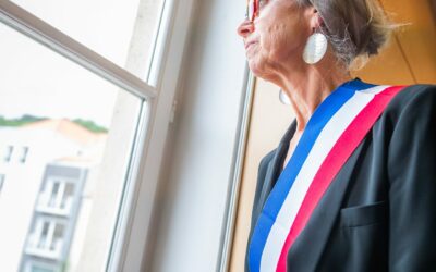 Femme regardant par la fenêtre avec écharpe tricolore.