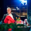 Personne assise avec microphone, décor lumineux.