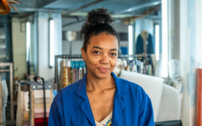 Femme souriante en blouse bleue dans un atelier.
