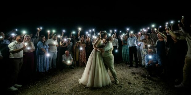 Mariage de nuit entouré d'invités avec téléphones illuminés.