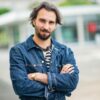 Homme en veste en jean croisant les bras.