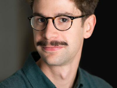 Portrait d'un homme avec lunettes et moustache.