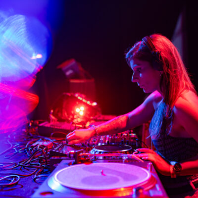 DJ mixant sur scène avec lumières colorées.