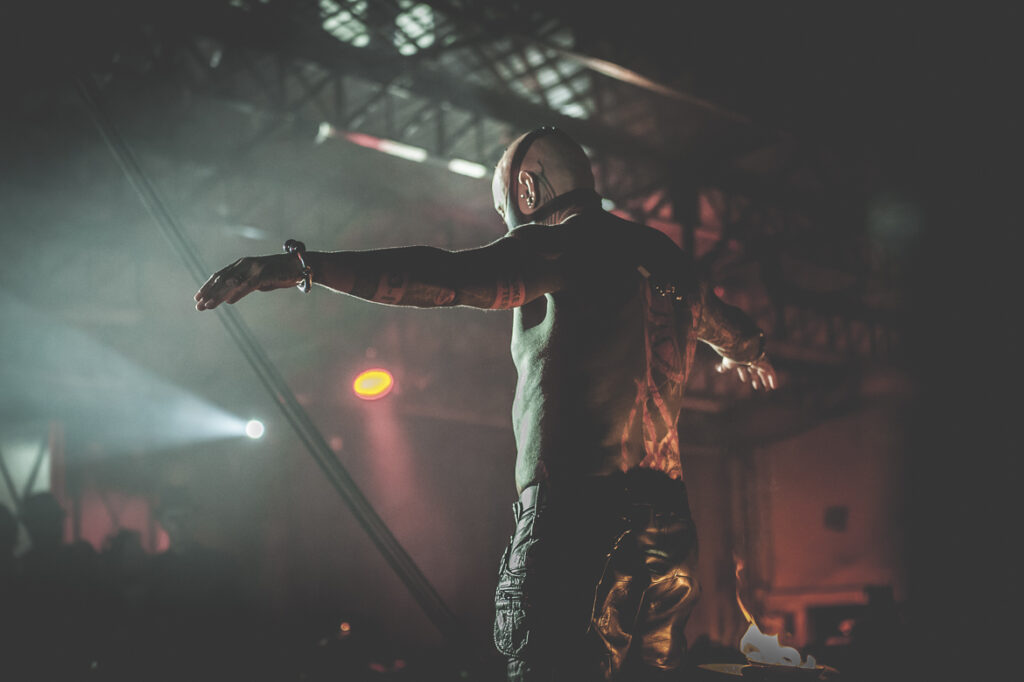 Spectacle sombre, homme tatoué bras ouverts.