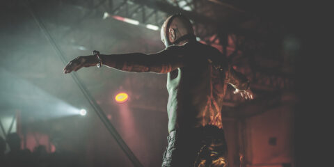 Spectacle sombre, homme tatoué bras ouverts.