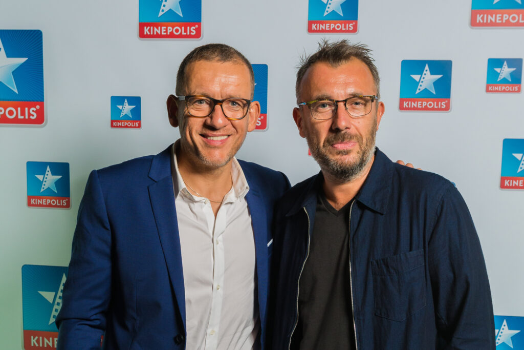 Deux hommes devant un logo Kinepolis.