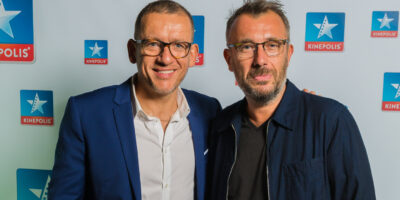 Deux hommes devant un logo Kinepolis.