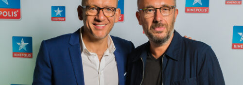 Deux hommes devant un logo Kinepolis.
